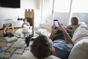 Family relaxing and playing in living room, texting and using digital tablet