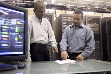 Two technicians standing in front of a network server