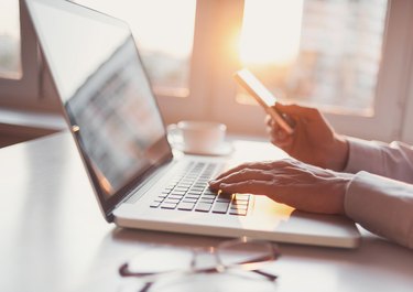 Place of work, man using laptop computer and smart phone