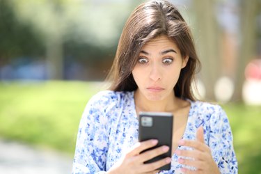 Perplexed woman checking phone in the street