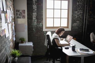 Dedicated creative businesswoman working at laptop in office