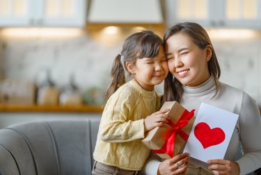 Daughter giving mother postcard ang gift